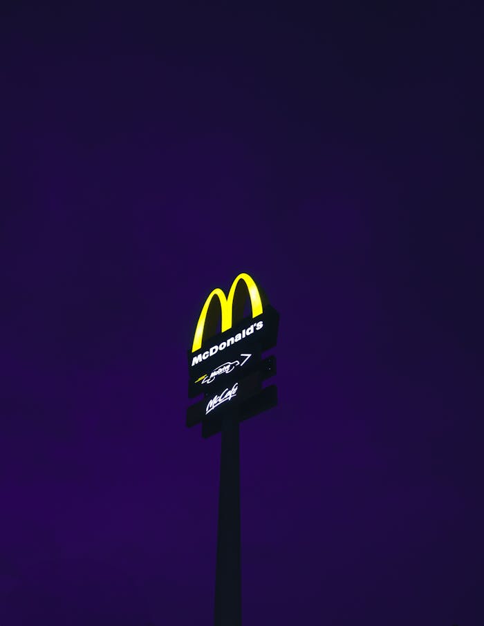 A glowing McDonalds sign stands out against a deep purple night sky.